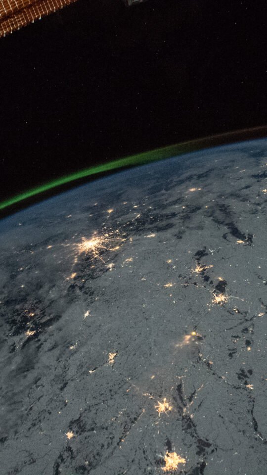 A green aurora above Earth’s night lights photographed from orbit