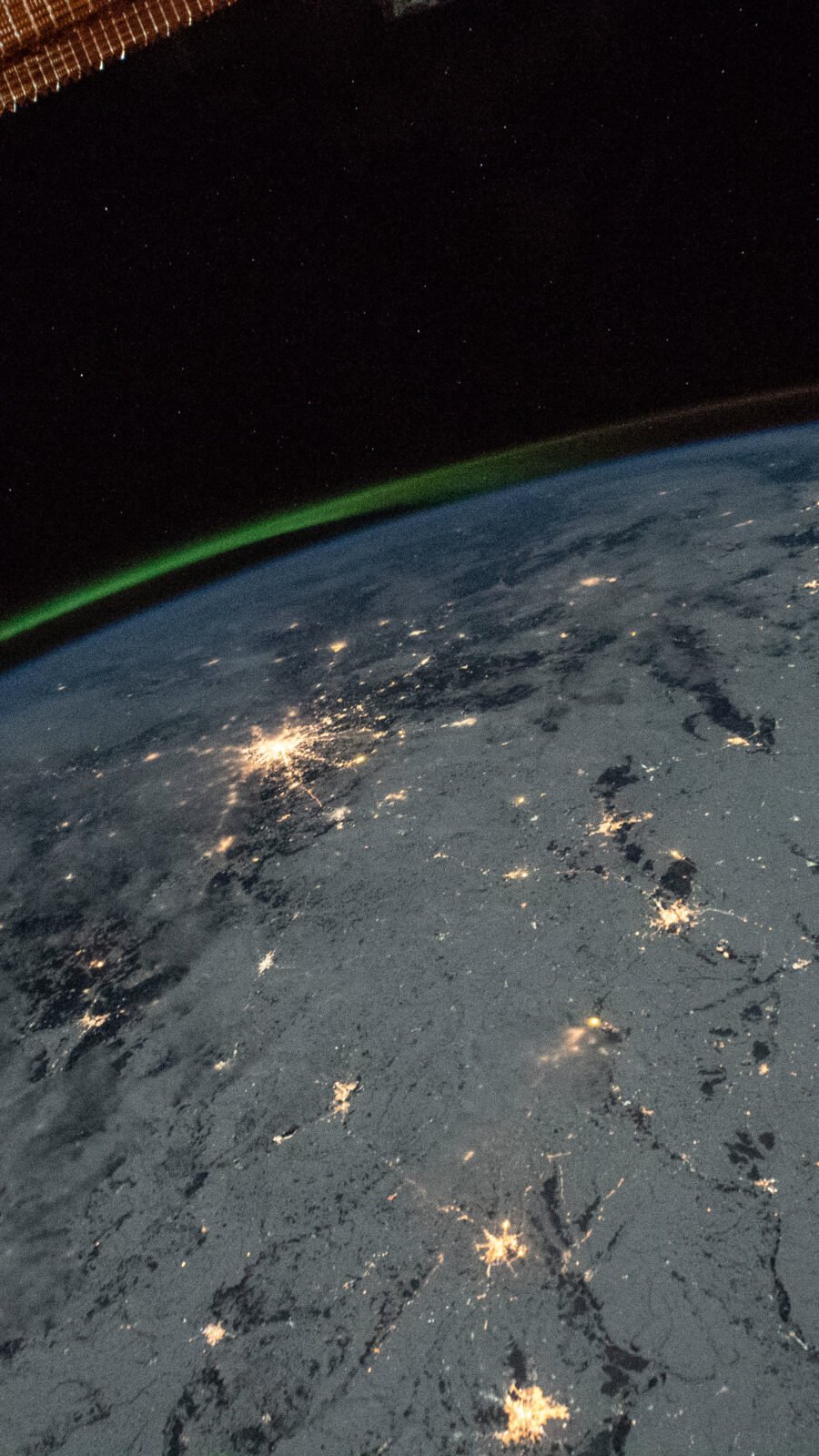 A green aurora above Earth’s night lights photographed from orbit