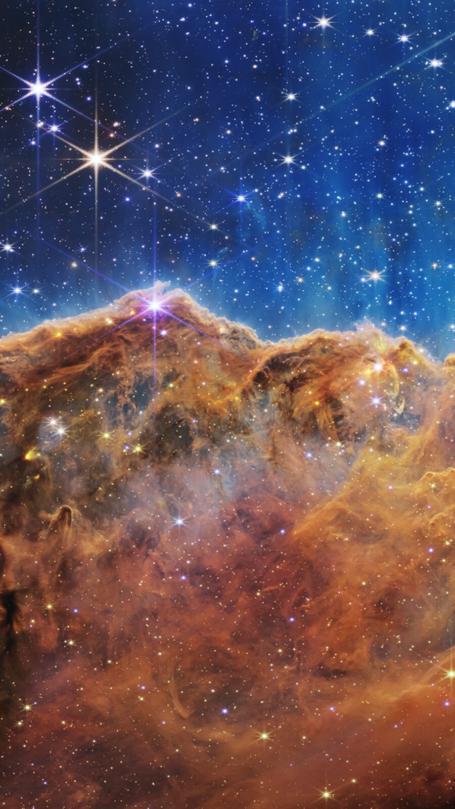 Golden Cosmic Cliffs in the Carina Nebula beneath a blue star field