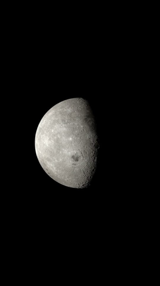 Half-lit Moon approaching against black space